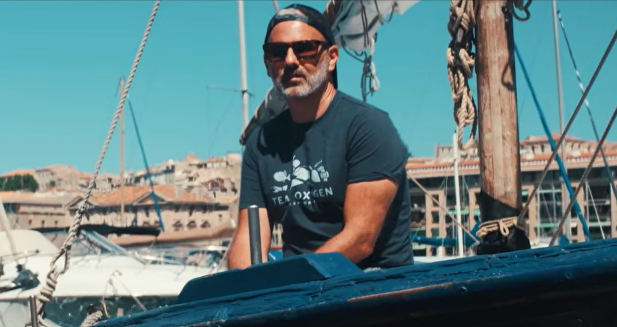 Karim Saari à bord d'une barque dans le Vieux-Port de Marseille, t-shirt Team Oxygen — court-métrage de la Fondation Green-Got