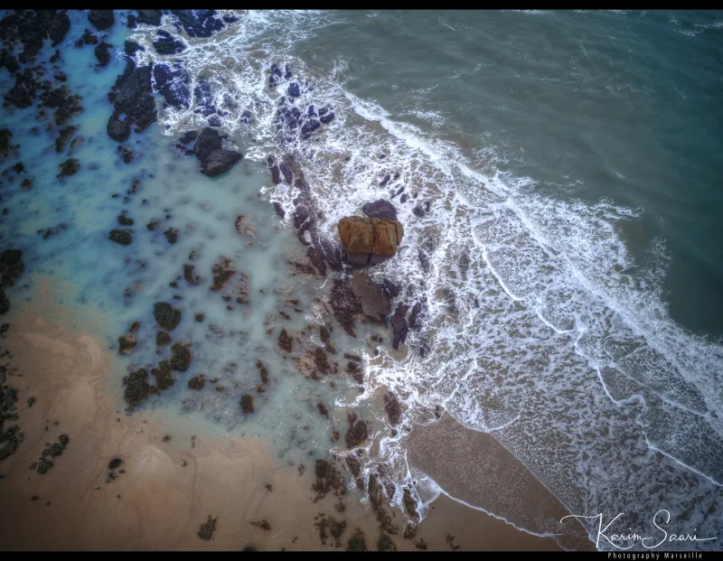 Vue aérienne de vagues blanches se brisant sur des rochers et une plage de sable — littoral méditerranéen