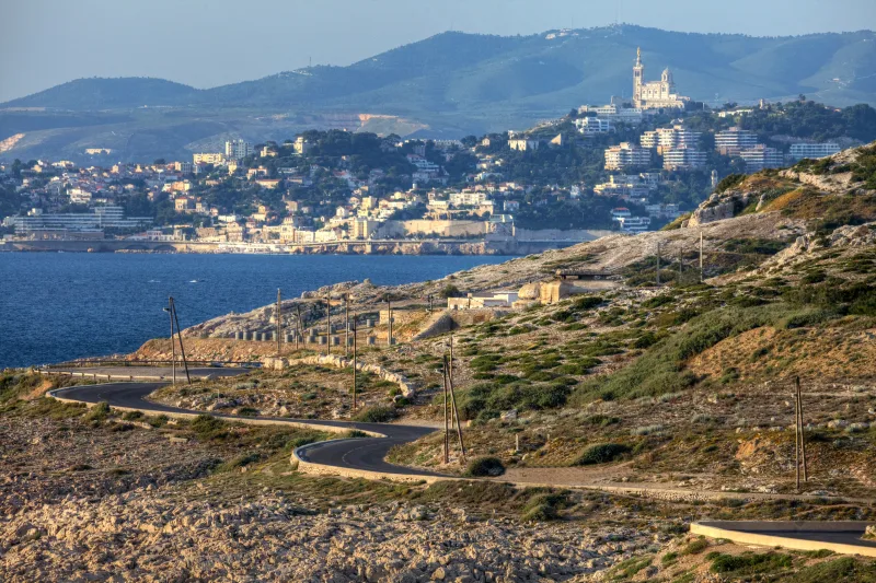 Vue panoramique sur Marseille depuis les hauteurs des Calanques, route sinueuse, Notre-Dame de la Garde visible