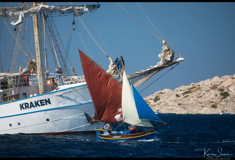 Pointu marseillais à voile rouge et blanc croisant le grand voilier Kraken dans les Calanques de Marseille