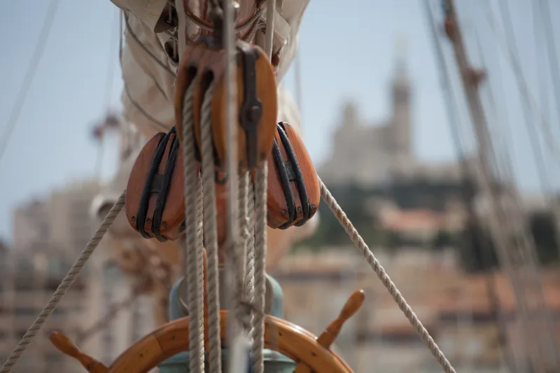Détail de poulies en bois sur un mât de voilier, Notre-Dame de la Garde en arrière-plan flou — Vieux-Port Marseille