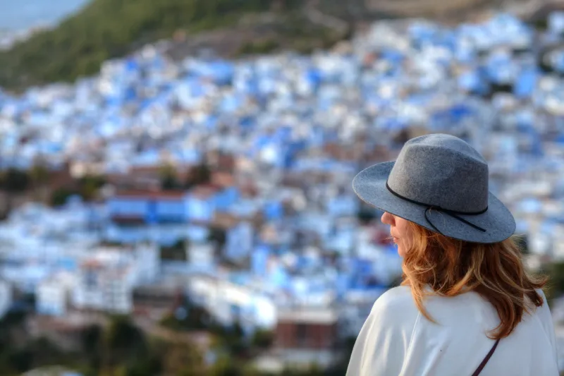 Femme de dos avec chapeau, ville bleue de Chefchaouen vue panoramique — photographe Maroc Karim Saari