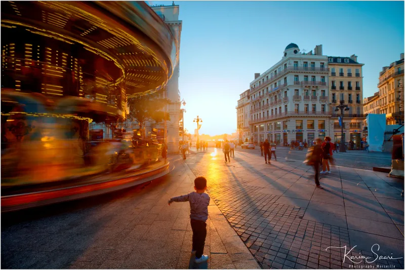 Carrousel flou et enfant sur la place du Vieux-Port au coucher de soleil — photographe Marseille Karim Saari