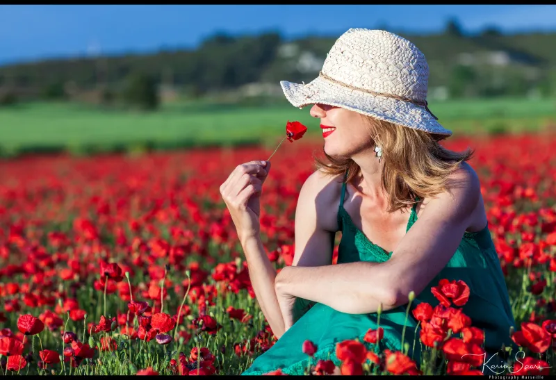 Femme au chapeau blanc avec un coquelicot dans un champ de coquelicots — photographe Provence Karim Saari