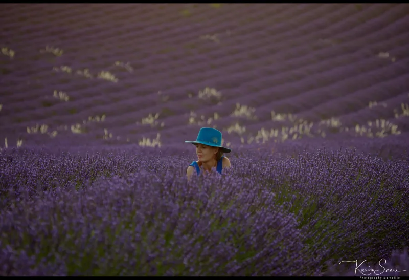 Femme au chapeau bleu dans un vaste champ de lavande violette — photographe paysage Provence Karim Saari