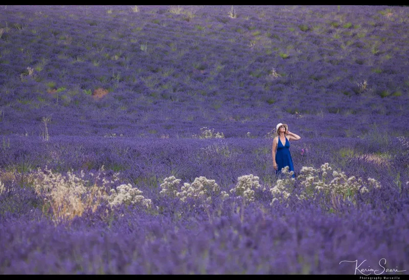 Femme en robe bleue marchant dans un champ de lavande violette — photographe Provence Karim Saari